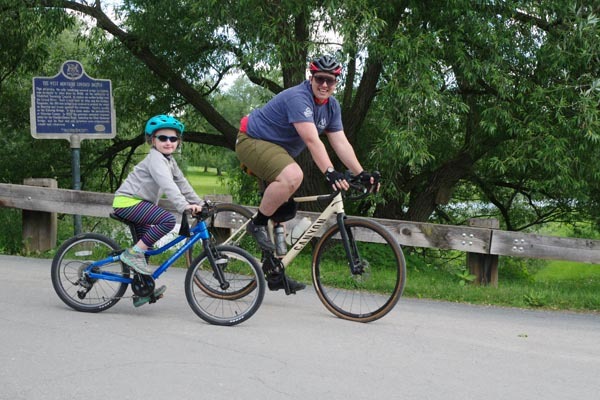 Adult and child ride bicycles together near the West Montrose covered bridge during the Out-Spok’n Bike-a-Thon.