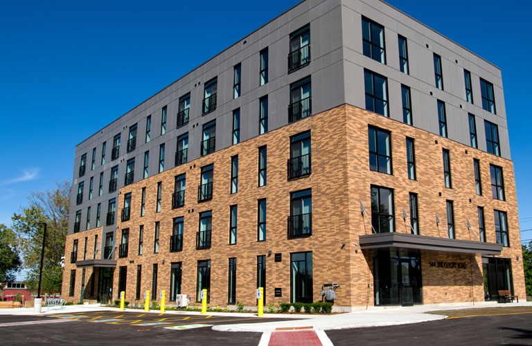 Modern multi-storey apartment building with brick and panel exterior under a clear blue sky.