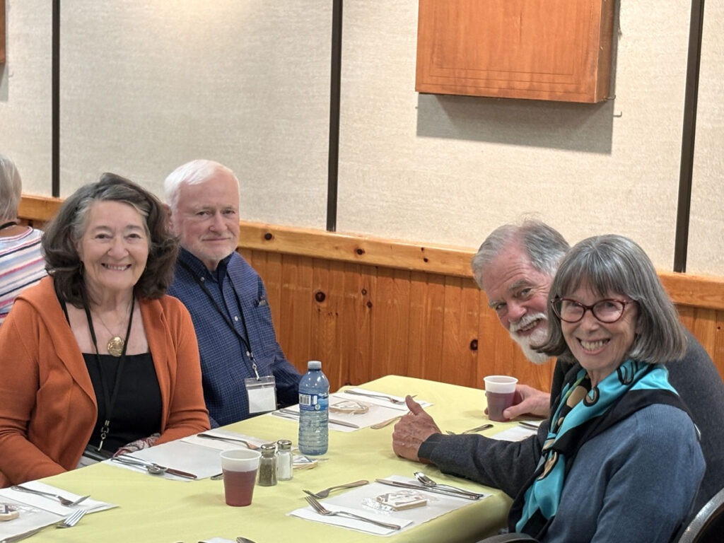 Four bus tour guests smile for a photo while seated together at lunch.